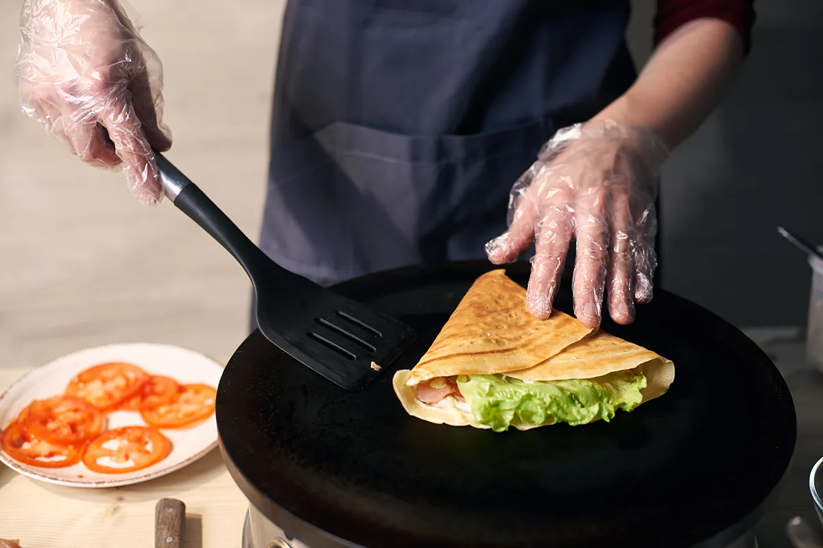 Chef cooking a filled crepe with lettuce and ham on a griddle at Me + Crêpe, a Chinese Restaurant in Pasadena